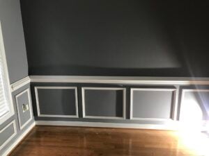 room with dark walls and white shadow box wainscoting